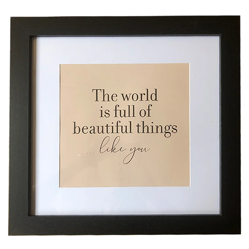Square black photo frame with a beige insert featuring the message 'The world is full of beautiful things... like you' in elegant typography.