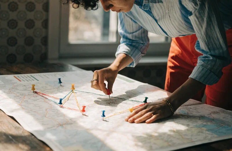 Planning a Trip on a Push Pin Map Someone using a push pin map to plan a future trip with yarn connecting different pins