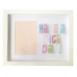 White rectangular photo frame with 'Have a Nice Day' colorful typography next to a pastel pink heart-patterned design.