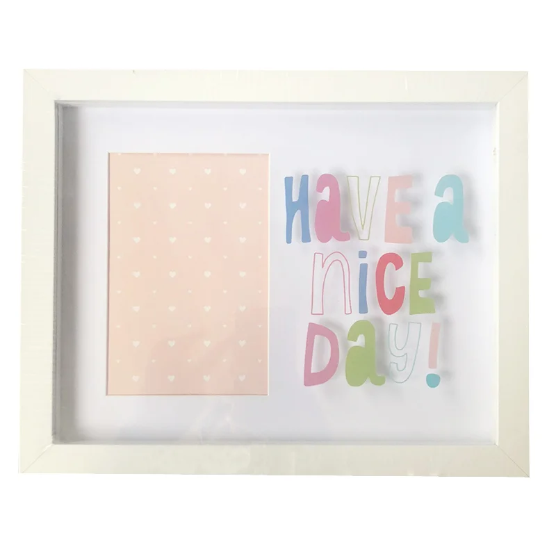 White rectangular photo frame with 'Have a Nice Day' colorful typography next to a pastel pink heart-patterned design.