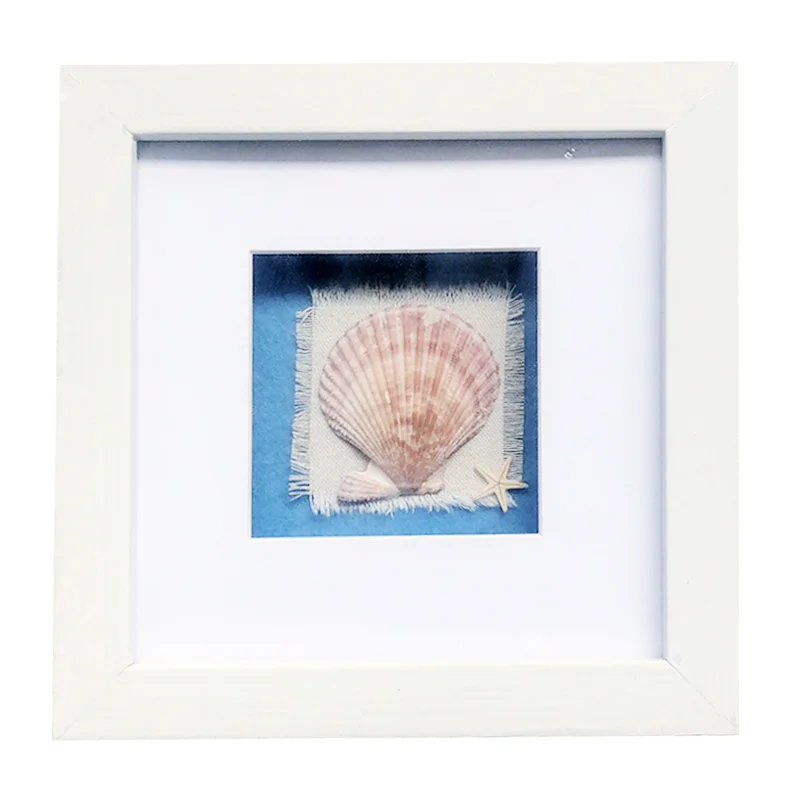 A white square photo frame featuring a seashell and a small starfish on a textured fabric background with blue accents.