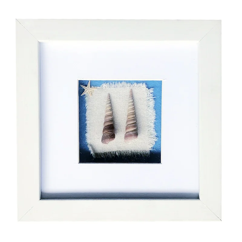 A white photo frame featuring a decorative display with two seashells and a small starfish on a textured fabric background.
