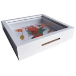 Angled view of a white wooden shadow box frame with a colorful decorative design inside, showcasing a floral theme.