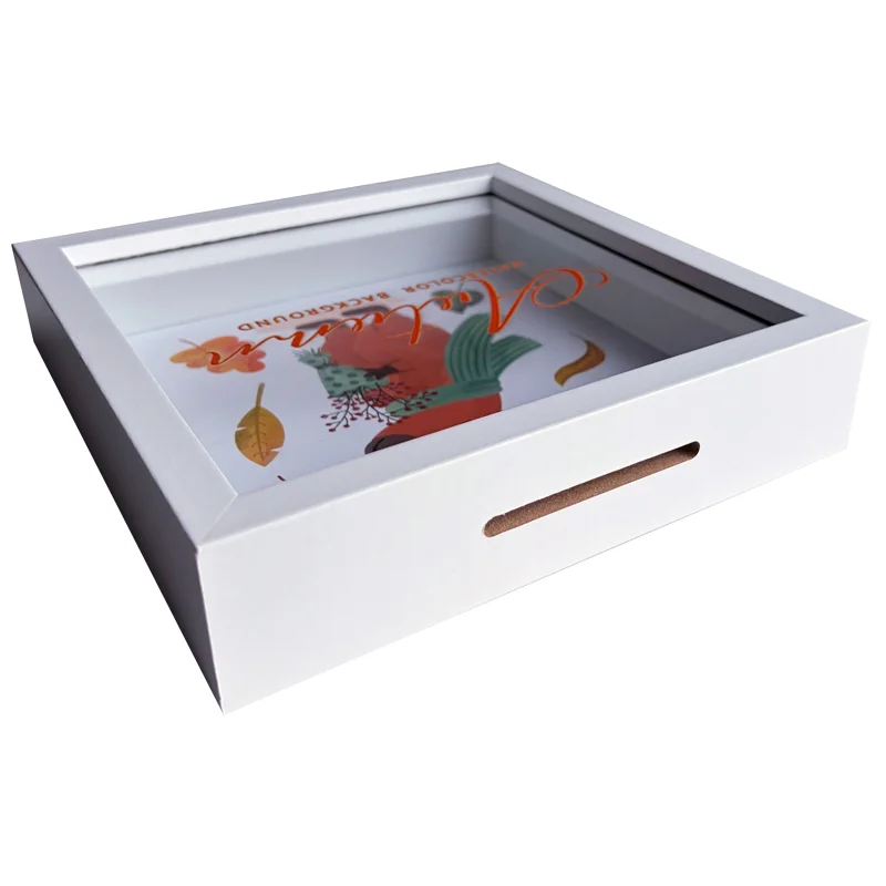 Angled view of a white wooden shadow box frame with a colorful decorative design inside, showcasing a floral theme.