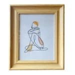 Light brown wooden photo frame displaying minimalist line art of a seated figure, featuring soft earthy tones on a white background.
