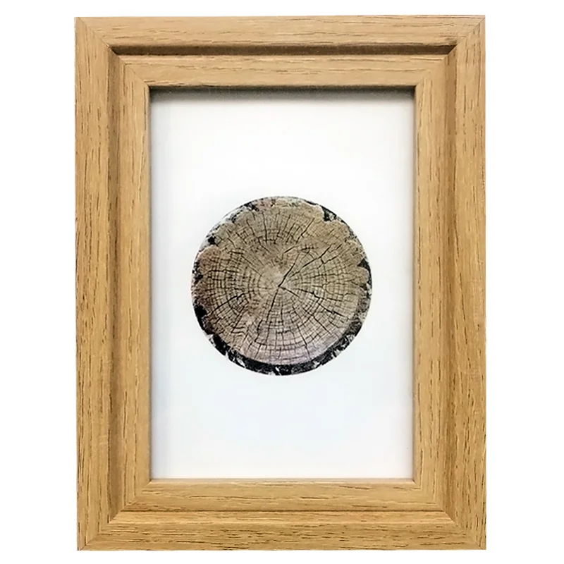 Wooden photo frame with natural wood finish showcasing an artistic tree ring print on a white background.