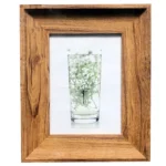 Rustic wooden photo frame surrounding an artistic image of a glass vase with delicate white flowers.