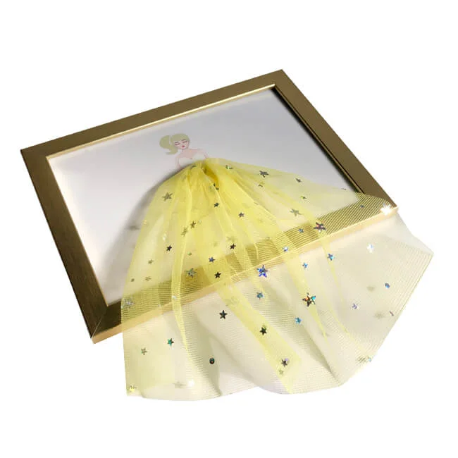 Golden-colored photo frame with a 3D artistic depiction of a yellow dress, featuring sparkling star embellishments.