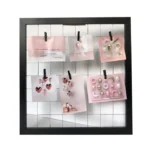 A black photo frame featuring a grid design holding six pastel cards with clips, showcasing decorative patterns and designs.