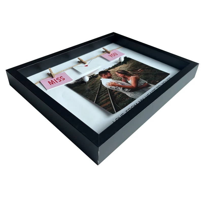 Black photo frame with a 'Miss You' design featuring mini clothespins holding decorative elements and a printed photo inside.