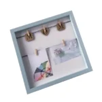 Square light blue MDF photo frame featuring wooden clips with letters spelling 'MOM' and small photos attached to a string.