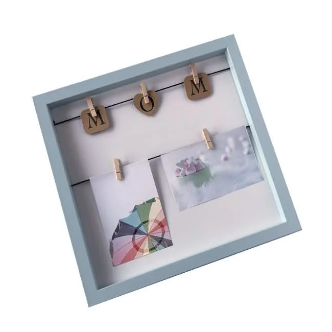 Square light blue MDF photo frame featuring wooden clips with letters spelling 'MOM' and small photos attached to a string.
