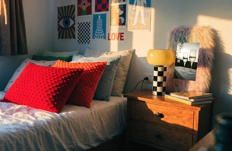 Gen Z Bedroom Decor Aesthetics A stylish Gen Z bedroom with textured pillows, colorful posters, and a furry frame on the nightstand.