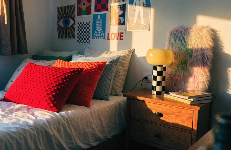 Gen Z Bedroom Decor Aesthetics A stylish Gen Z bedroom with textured pillows, colorful posters, and a furry frame on the nightstand.