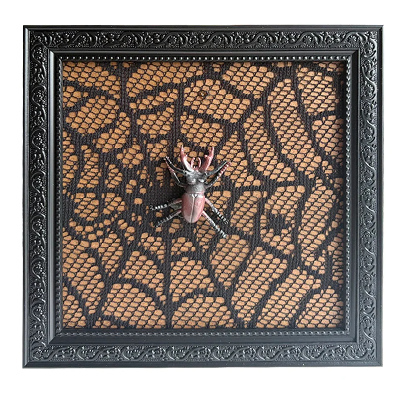 Ornate black frame with decorative lace background and a beetle ornament in the center for artistic home decor.