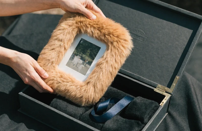 Premium Packaging for Gift Frames A plush furry photo frame being placed into a high-quality gift box with a silk ribbon.