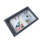 A gray wooden collage photo frame with two compartments, featuring colorful images and hanging clips inside.