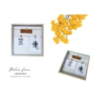 Square MDF wooden wall art frame with 'Home' wooden sign and two hanging decorative prints, paired with yellow flowers.