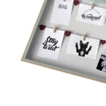 Photo frame with wooden border displaying small prints of text and images clipped with pegs and heart pins.