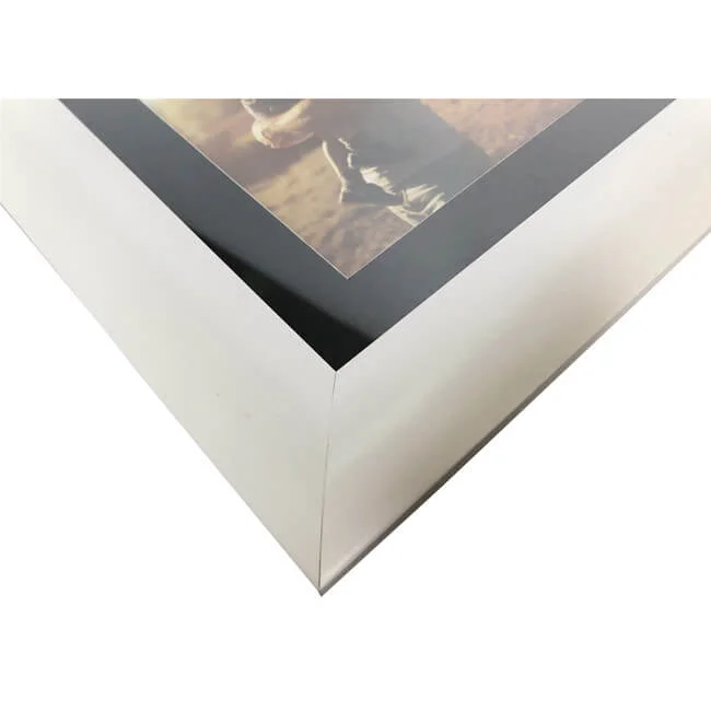 Close-up view of a sleek modern white photo frame with a glossy black inner border showcasing a partial photograph.