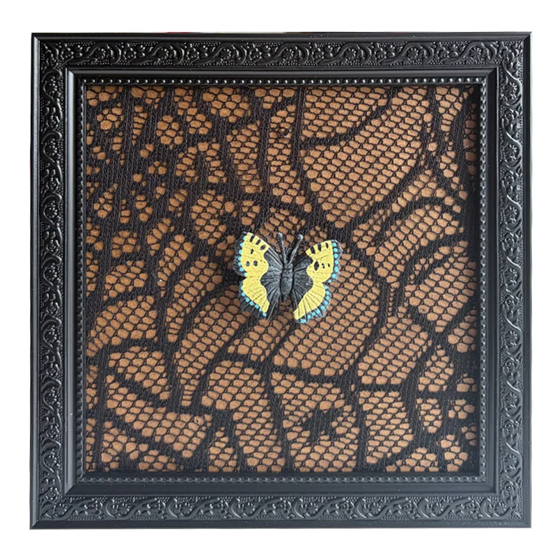 A decorative black photo frame with intricate designs featuring a lace-patterned background and a yellow and black butterfly.
