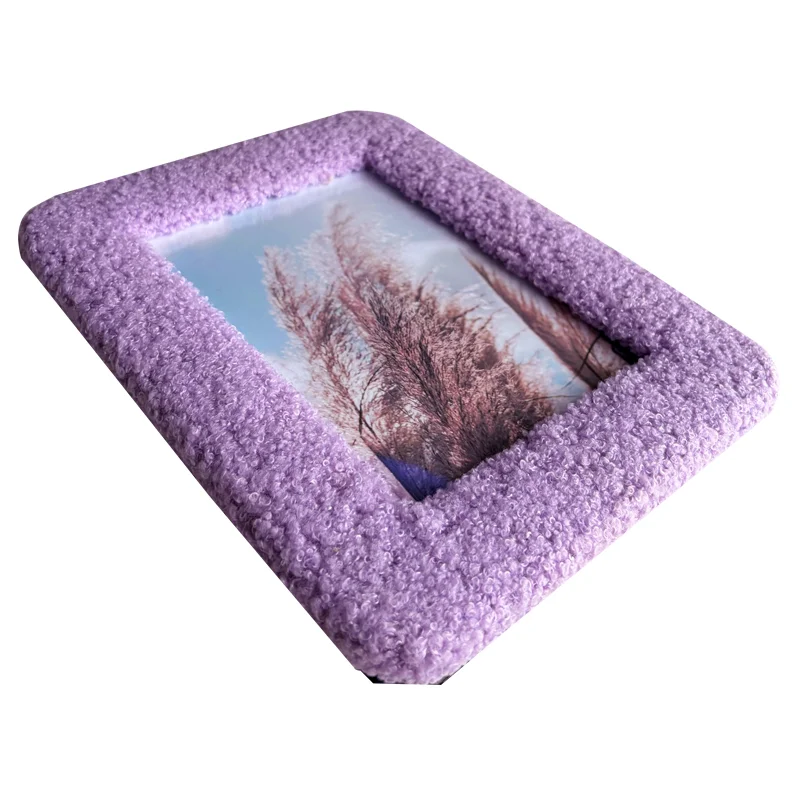 Close-up of a purple textured photo frame featuring a serene landscape of grasses against a blue sky.