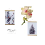Two photo posters with wooden frames featuring a reindeer and snowy tree, accompanied by a pink orchid for decoration.