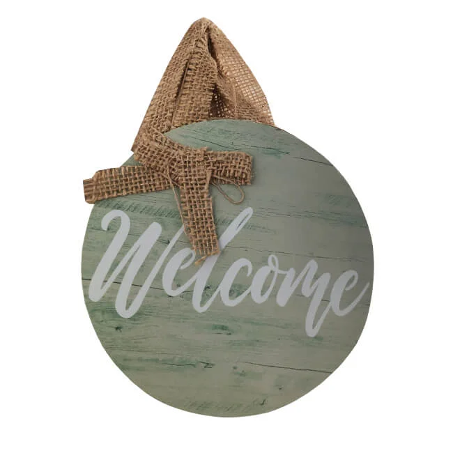 Round rustic wooden welcome sign with greenish finish and white lettering, featuring a burlap ribbon for hanging.