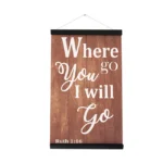 Decorative wall sign with wooden texture displaying the Bible verse 'Where You Go, I Will Go' from Ruth 1:16 in white text.