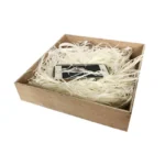 A wooden box filled with shredded paper holding a smartphone, providing a protective packaging solution.