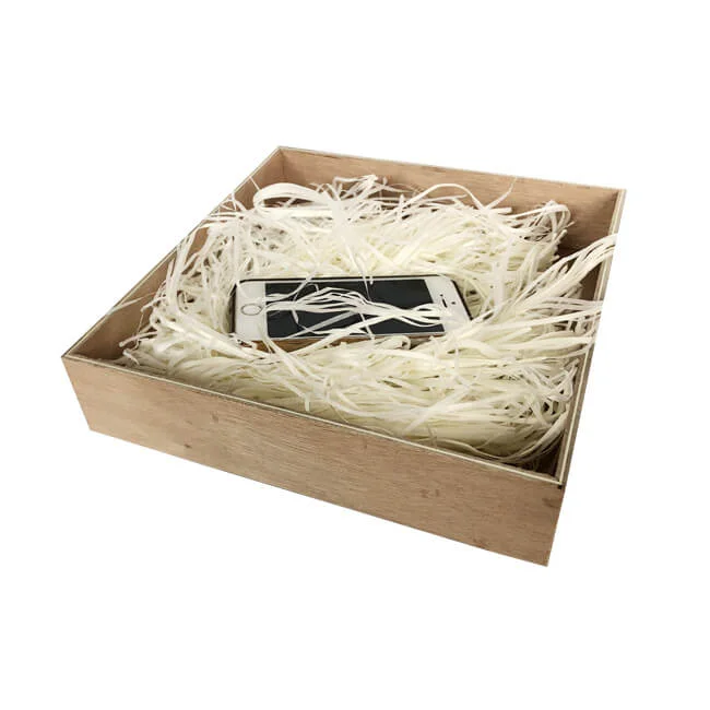 A wooden box filled with shredded paper holding a smartphone, providing a protective packaging solution.