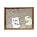 A wooden framed bulletin board with a fabric background, featuring two pinned notes listing a to-do list and tasks.