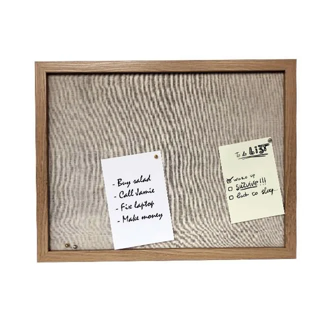 A wooden framed bulletin board with a fabric background, featuring two pinned notes listing a to-do list and tasks.