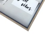 Close-up of a wooden photo frame containing a white card with 'Good Vibes' written in black cursive font.