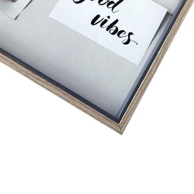 Close-up of a wooden photo frame containing a white card with 'Good Vibes' written in black cursive font.