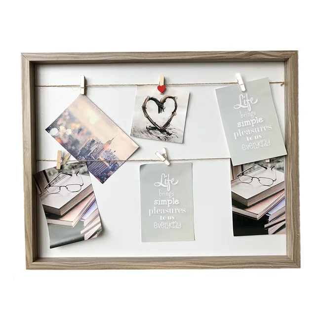 A wooden photo collage frame featuring multiple photos and quotes clipped with small pegs on strings.