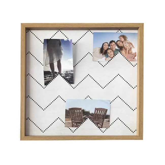 Square wooden photo frame with a white chevron-patterned background displaying three photos clipped on wires.