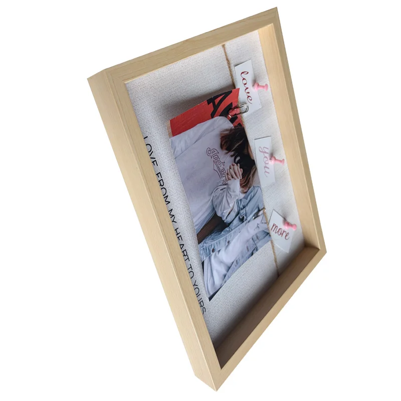 Angled view of a light wooden photo frame displaying a decorative design with a photo, text cards, and pink clips.