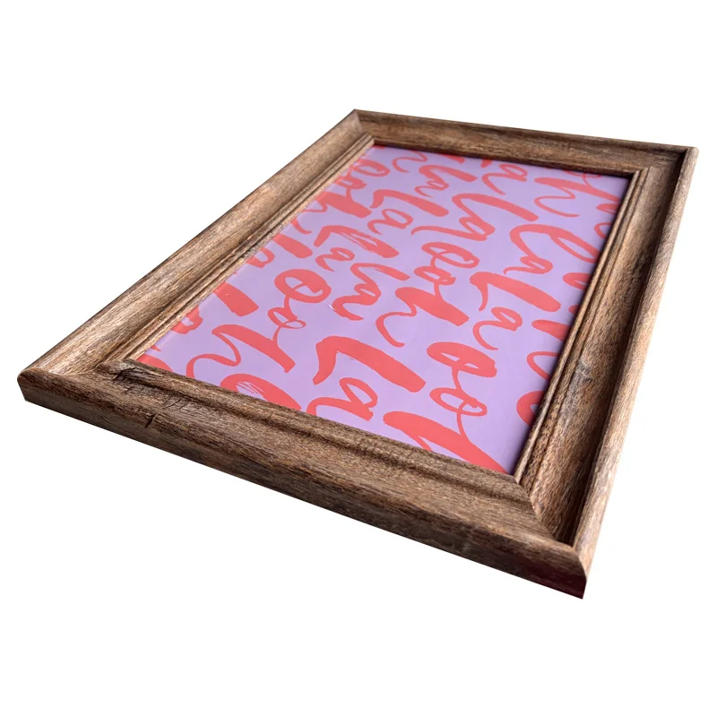 A rustic wooden photo frame displaying a pink pattern with red abstract text on it, angled for a modern presentation.