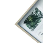 A natural wooden photo frame showcasing a tropical leaf graphic with vibrant green foliage and white background.