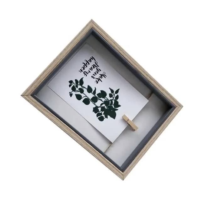 Wooden shadow box photo frame displaying a botanical print and decorative text, held by a small clip, on a white background.